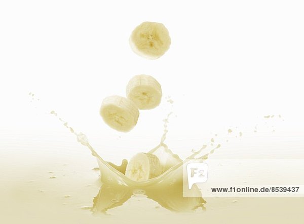 Bananenscheiben fallen in Bananensaft
