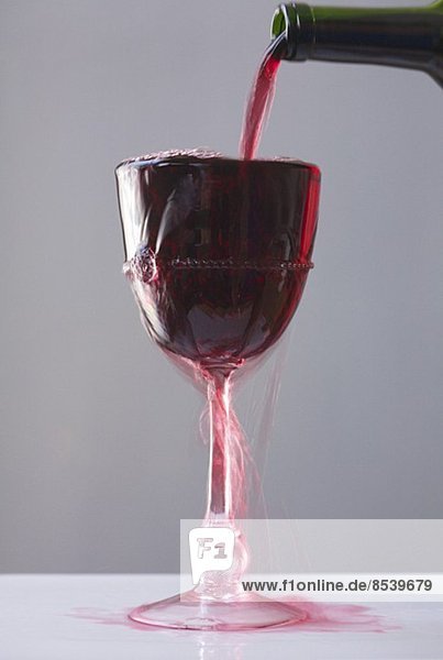 Rotwein wird in übervolles Weinglas gegossen