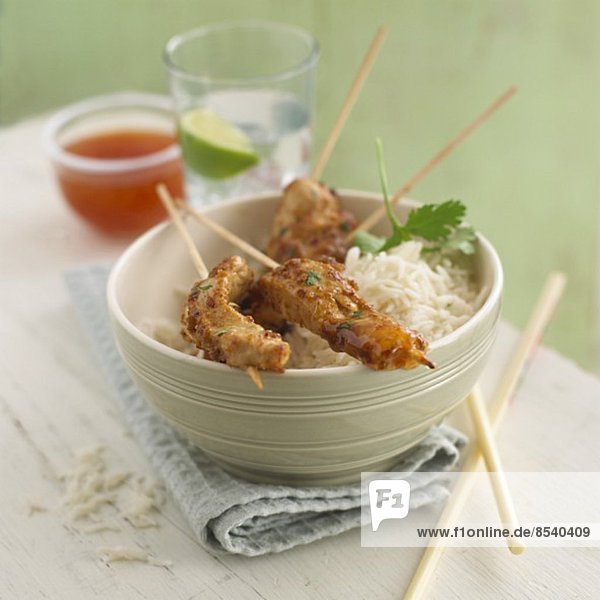 Chicken satay skewers on a bed of rice