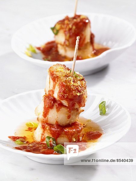 A skewer of scallops with tomato sauce