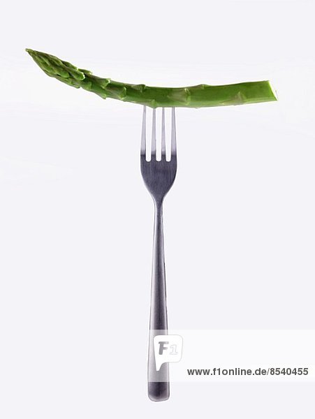 A stem of green asparagus on a fork