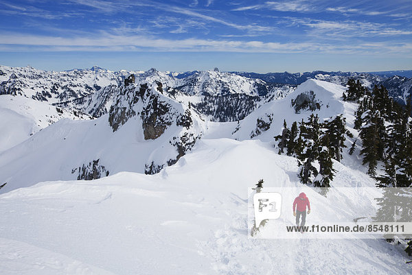 A climber in a red jacket on the summit of Snoqualmie Peak in the Cascades range of mountains in Washington state  USA.