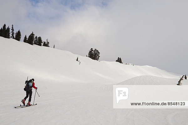Ein Skifahrer häutet einen Schneehang hinauf zum Gipfel eines Berggipfels.