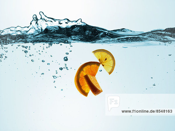 Flüssigkeit in einem Behälter  mit bewegtem Wasser  Luftblasen und Zitronen- und Orangenscheiben.