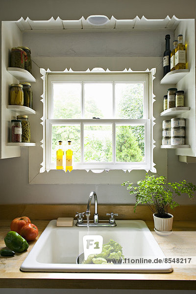 Küchenfenster  mit Regalen und einem traditionellen Spülbecken  Wasserhahn und fließendem Wasser zum Waschen von Gemüse.