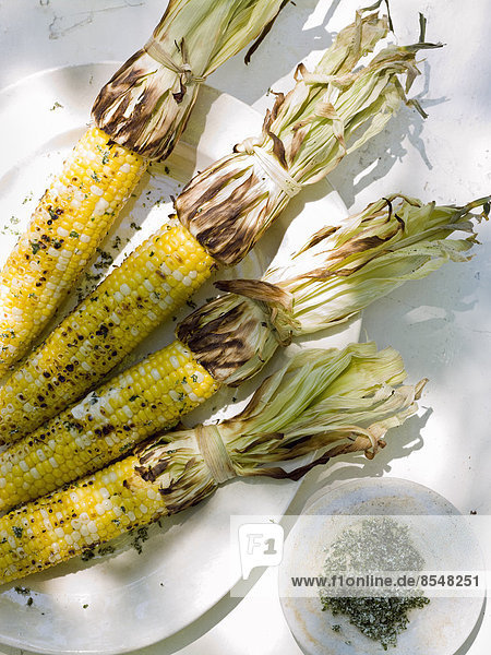 A buffet table set up in a garden for al fresco meal. Sweetcorn  grilled corn on the cob.