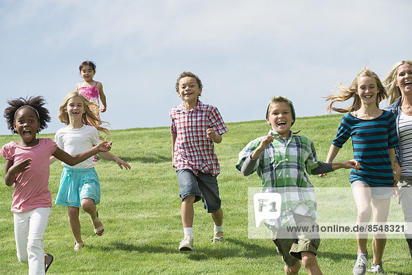 A group of children running across a grass field.