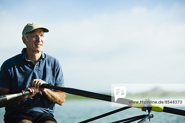 Ein Mann mittleren Alters rudert mit einem einzigen Totenkopf-Ruderboot auf dem Wasser.