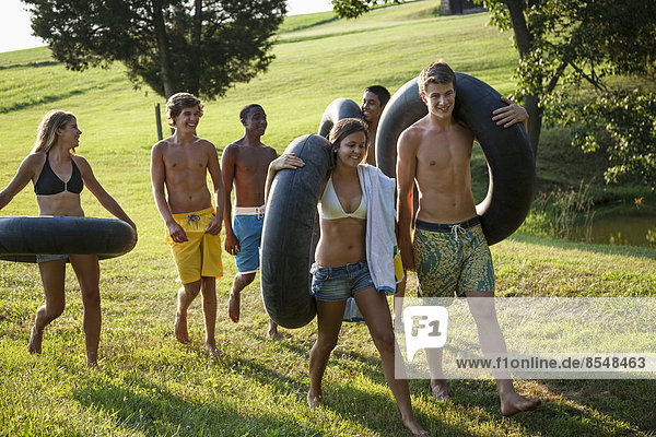 Eine Gruppe von Jugendlichen  Jungen und Mädchen  die Handtücher und Schwimmwagen halten und schwimmen gehen.