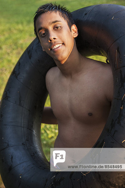 Ein kleiner Junge  ein Teenager mit nackter Brust  mit einem schwarzen Schwimmer schwimmt ihm über die Schultern.