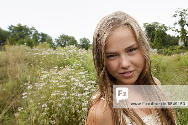 A young girl with long blonde hair playing in the long grass.