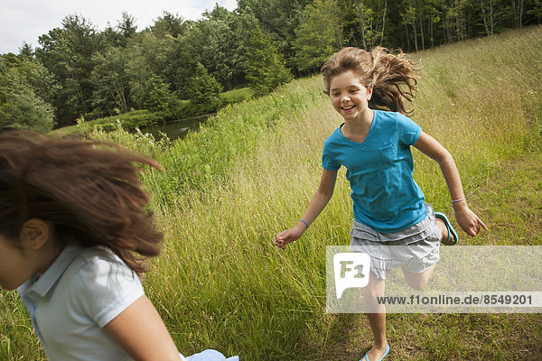 Two children  girls playing chase and running along a path.