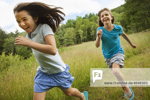Two children  girls running and playing chase  laughing in the fresh air.