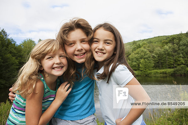 Three young girls  friends side by side  posing for a photograph in the open air.