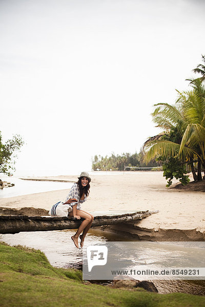 Eine junge Frau auf einer Holzbrücke über einen kleinen Bach auf der Halbinsel Samana in der Dominikanischen Republik.