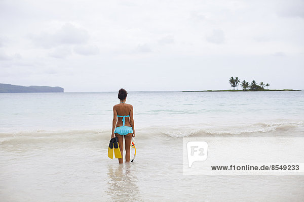 A young woman in shallow water with snorkelling gear on Samana Peninsula in the Dominican Republic.