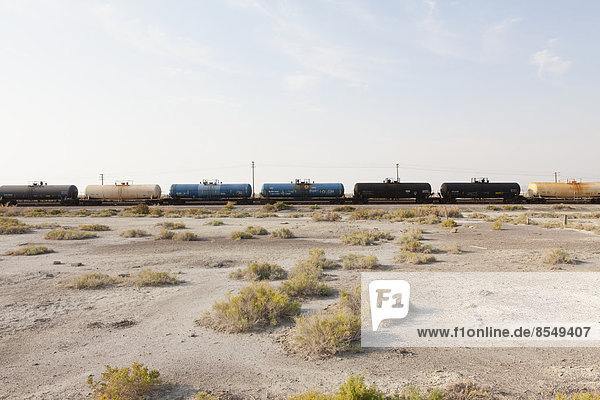 Ein Güterzug auf den Gleisen  der durch die Wüste fährt. Güterwaggons.