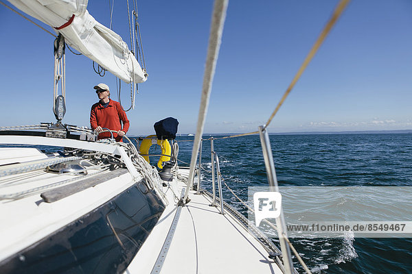 Middle aged man steering sailboat on Puget Sound  Washington  USA