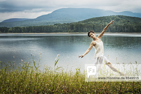 Eine Frau tanzt anmutig unter freiem Himmel entlang des Seeufers bei Woodstock  New York State  USA