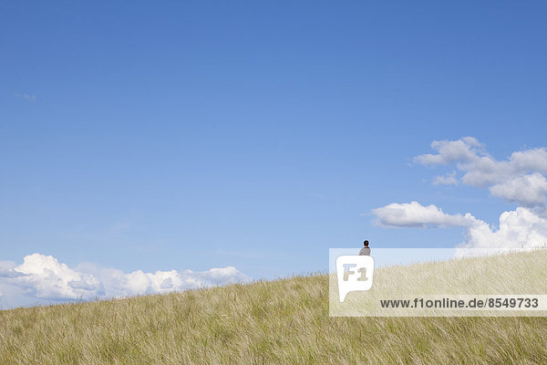 Ein Mann  der auf dem Kamm eines Hügels steht.