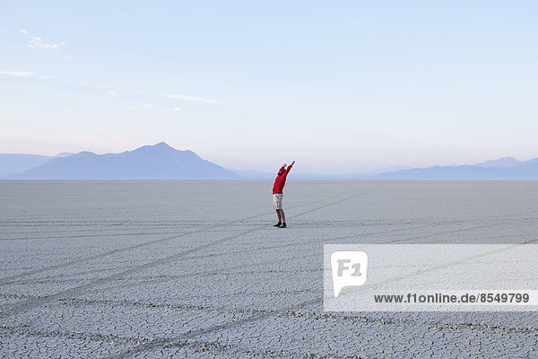 Ein Mann mit erhobenen Armen im Morgengrauen in der Black Rock-Wüste in Nevada.