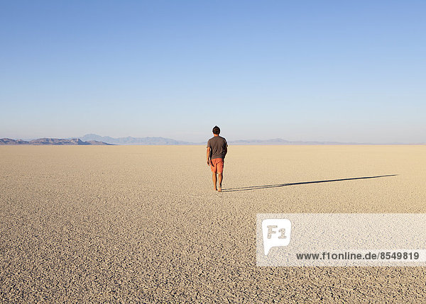 Mann läuft durch eine flache Wüstenlandschaft