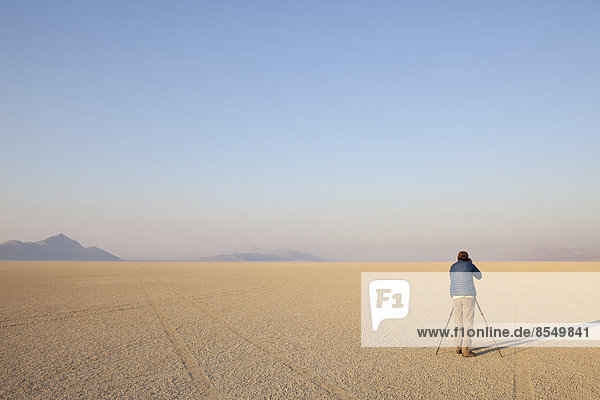Man with camera and tripod on the flat saltpan or playa of Black Rock desert  Nevada.