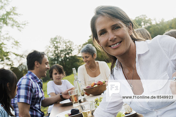 Eine Familie und Freunde bei einer Mahlzeit im Freien. Ein Picknick oder Buffet am frühen Abend.