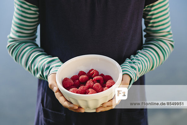 Neunjähriges Mädchen hält Schale mit Bio-Himbeeren