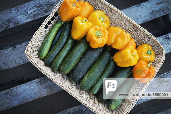 Bio-Zucchini im Korb mit gelben und orangefarbenen Paprikaschoten
