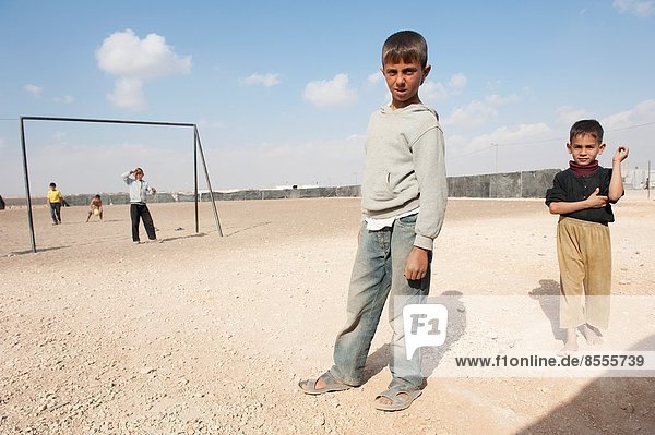 Al Za'atari  Al Za'atari  Al Mafraq  Jordan. Five Syrian refugee boys playing on UNHCR refugee camp child safe place football or soccer field in the middle of the Jordanian dessert.