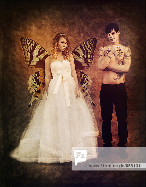 Wedding picture  bride and groom  bride with butterfly wings and a bare chested groom with tattoos  holding a cigarette