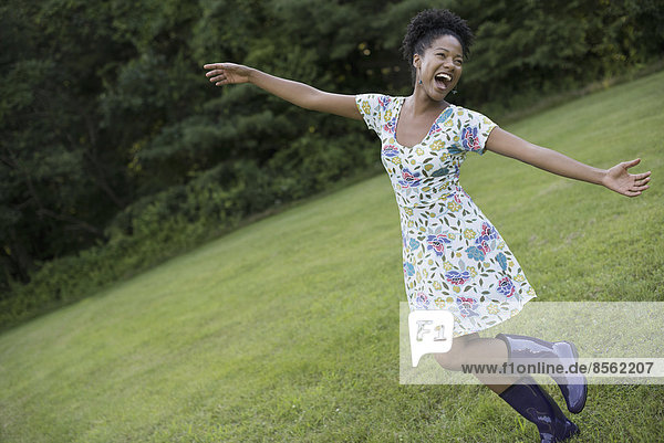 A young woman in a summer dress with her arms outstretched  celebrating freedom.