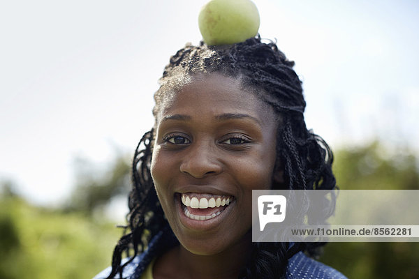 Eine junge Frau mit einem grünen Apfel auf dem Kopf.