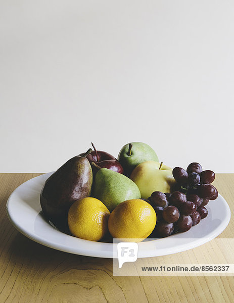 Plate of organic fresh fruit (tangerines  grapes  red bartlett pear  green anjou pears apples)