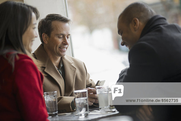 Stadtleben. Eine Gruppe von Menschen  die unterwegs sind  Mobiltelefone benutzen und miteinander sprechen. In einem Café.