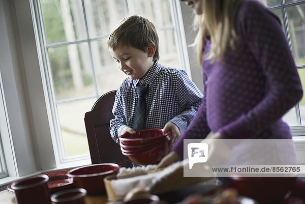 Ein Familienhaus. Zwei Kinder decken den Tisch mit Geschirr für eine Mahlzeit.