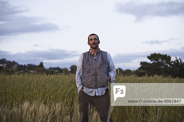 Ein Mann  der an einem Feld mit Getreideanbau steht  beim Sozialfürsorge- und Arbeitsprojekt  dem Obdachlosen-Gartenprojekt in Santa Cruz.