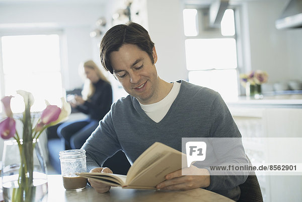 Couple Relaxing at Home  man reading  woman using smartphone