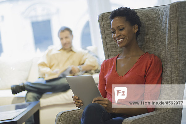 Couple relaxing at home reading  woman with tablet