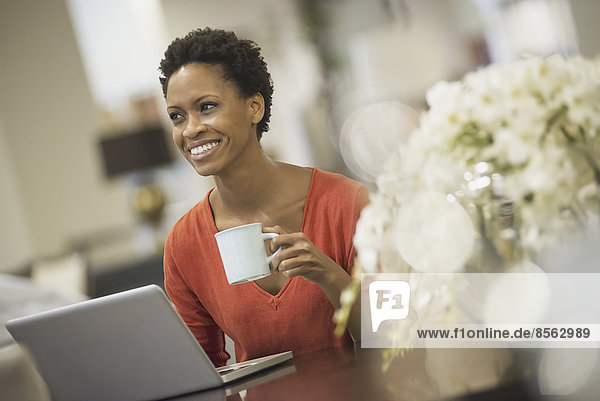 Frau entspannt sich zu Hause mit Laptop und Kaffee