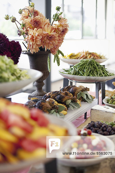 Biologisch zubereitete Salate  Gemüse und Obst auf Gerichten  die für eine Party ausgelegt sind. Ein gedeckter Tisch. Blumen in einer Vase. Ein Essensstand auf einem Bauernhof.