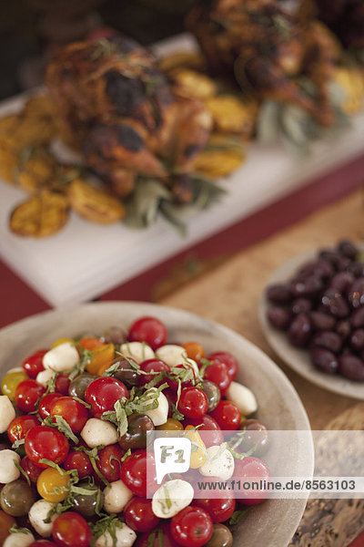 Ein für eine Party gedeckter Buffettisch. Bio-Essen. Salate und ein Hühnergericht.