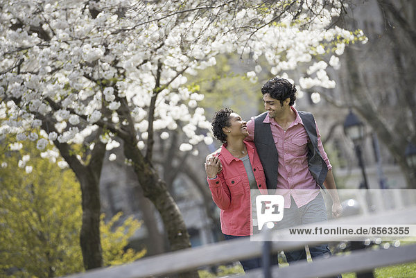 People outdoors in the city in spring time. New York City park. A couple  man and woman looking into each others eyes.