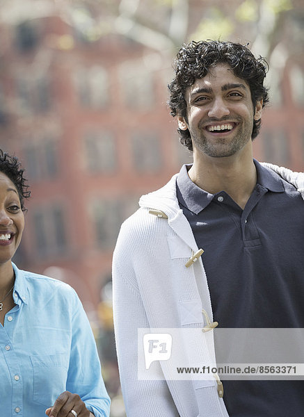 People outdoors in the city in spring time. New York City park. A man and woman side by side  smiling.