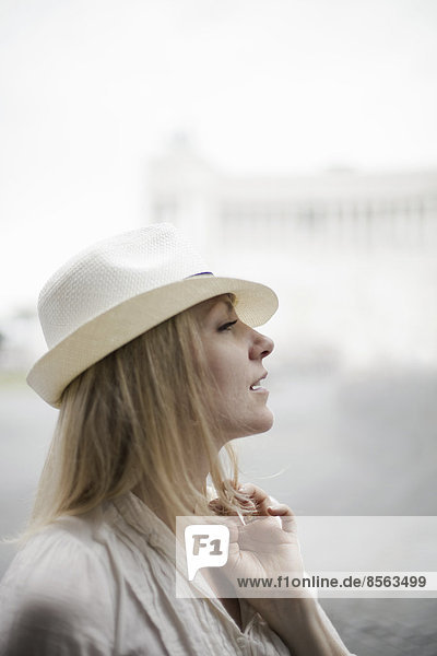 A woman with blonde hair wearing a cream panama hat.