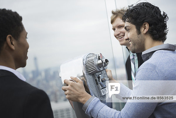 New York City. Eine Aussichtsplattform mit Blick auf das Empire State Building. Drei junge Männer mit Blick über die Stadt.