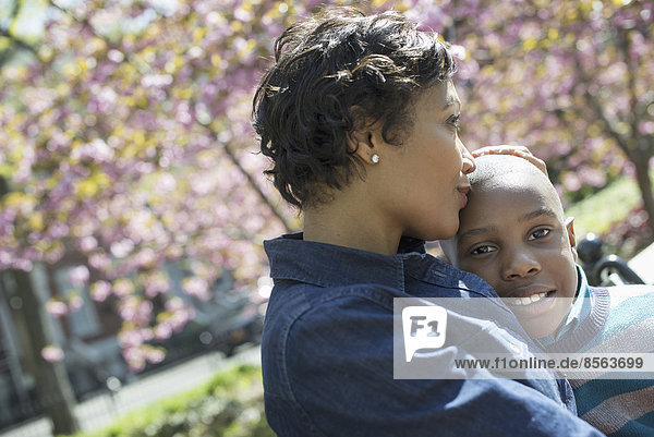 Ein New Yorker Stadtpark im Frühling. Sonnenschein und Kirschblüte. Eine Mutter und ihr Sohn verbringen Zeit miteinander.
