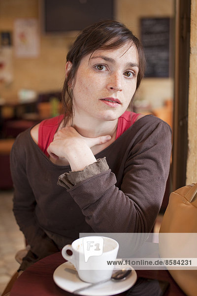Junge Frau sitzt vor dem Café