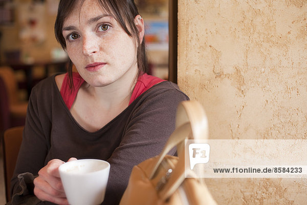 Junge Frau sitzt vor dem Café